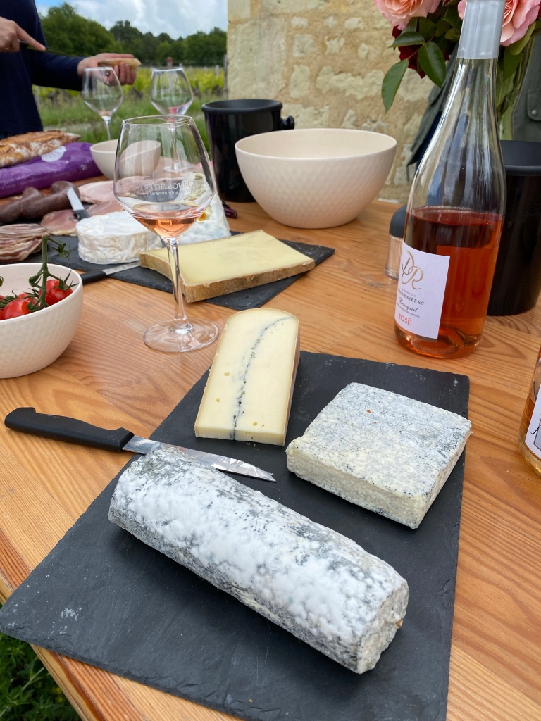Table de produits régionaux de Bourgueil, dont un verre et une bouteille de vin rosé AOC Bourgueil, des fromages et de la charcuterie